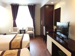A hotel room with two beds, a TV, a desk, a chair, and a small table with cups and a tray. - Golden Lotus Halong Hotel (Bai Chay)