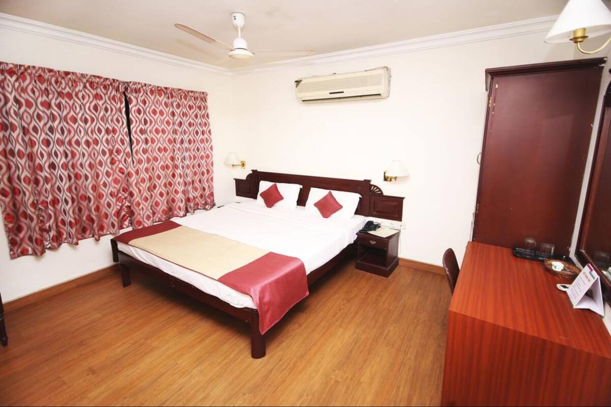 A neatly arranged hotel room with a wooden bed, a desk, and a chair.