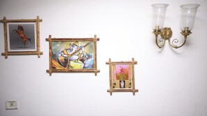 A wall with three framed artworks and two wall-mounted light fixtures. - Archana Inn (Kanayannur)