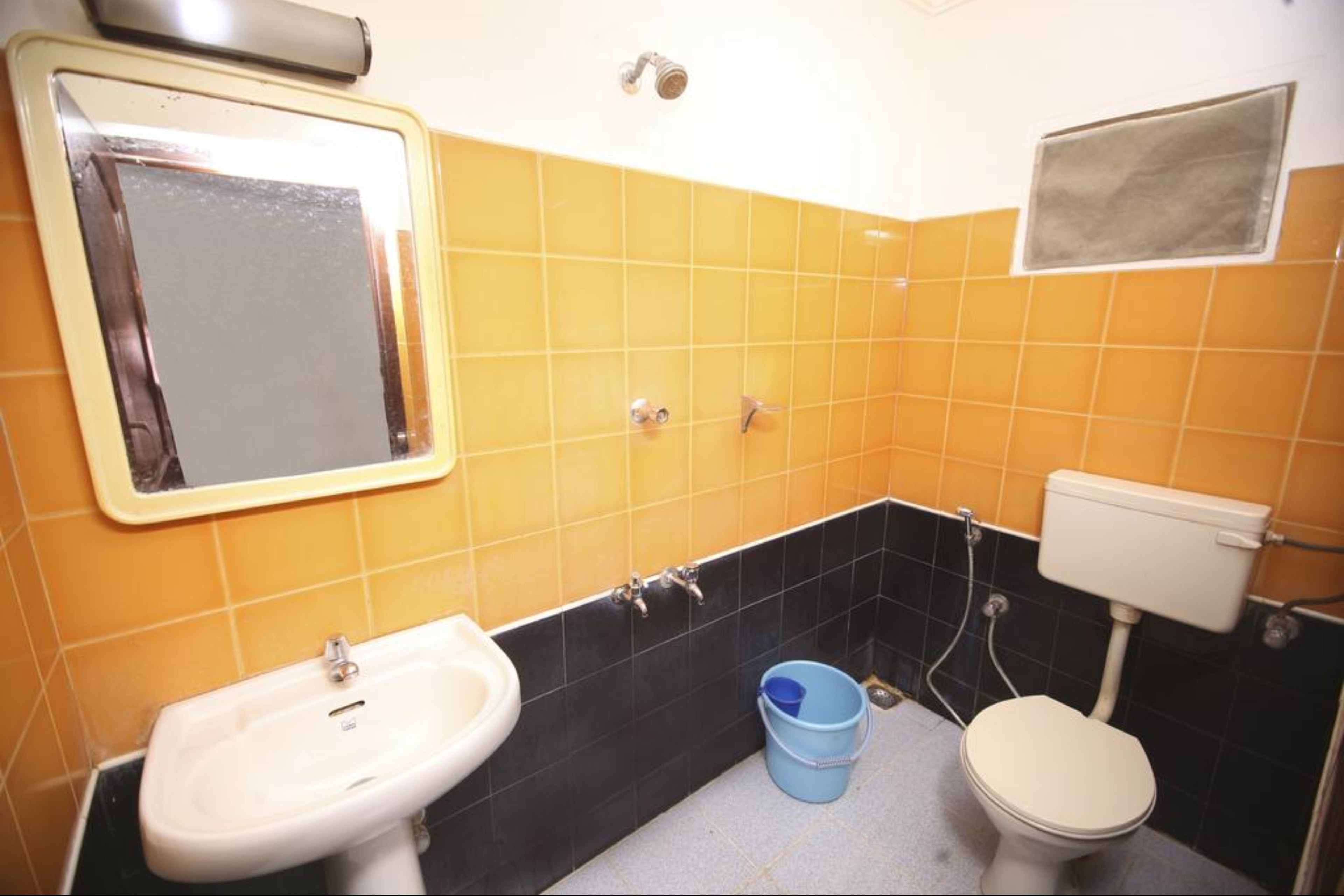 A bathroom with yellow and black tiles, a sink, a toilet, and a mirror.
