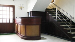 A reception desk, a staircase, and a door in a hotel lobby. - Archana Inn (Kanayannur)