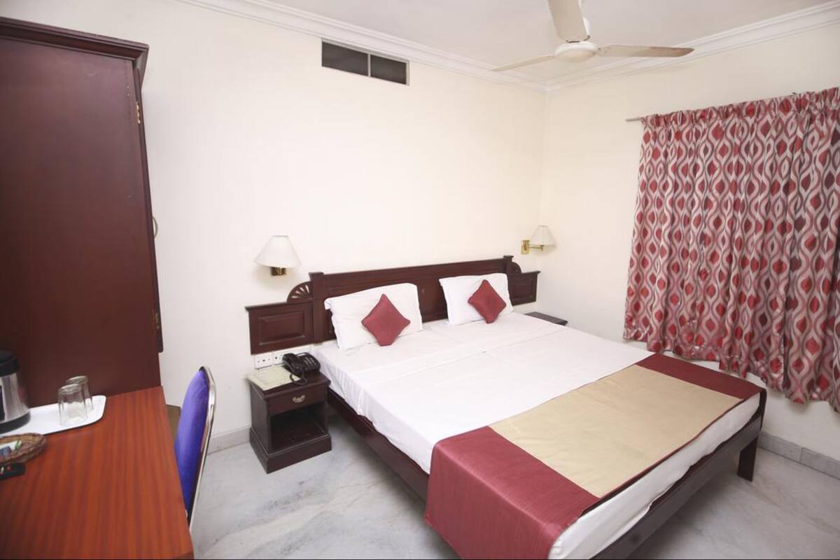 A hotel room with a bed, bedside table, lamp, and a wardrobe.