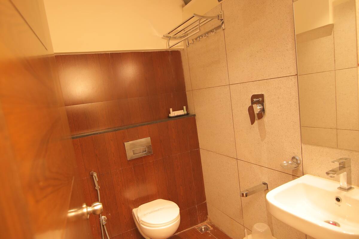 A bathroom with a wooden floor, a white toilet, a sink, and a shower area.