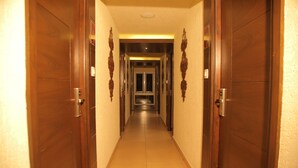 A long, narrow hallway with wooden doors on either side, leading to a central door at the end. - Canyonsun (Chennai)
