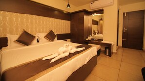 A hotel room with a large bed, a bedside table, a mirror, and a wardrobe. - Canyonsun (Chennai)