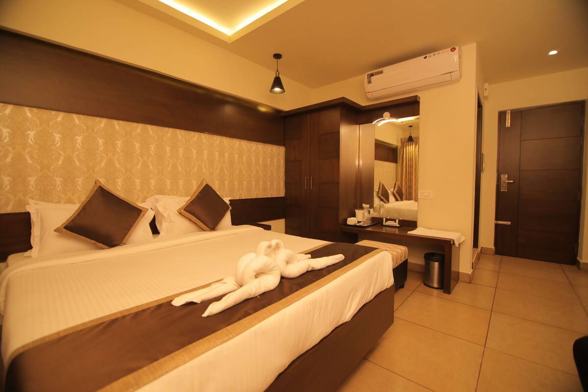 A hotel room with a large bed, a bedside table, a mirror, and a wardrobe.