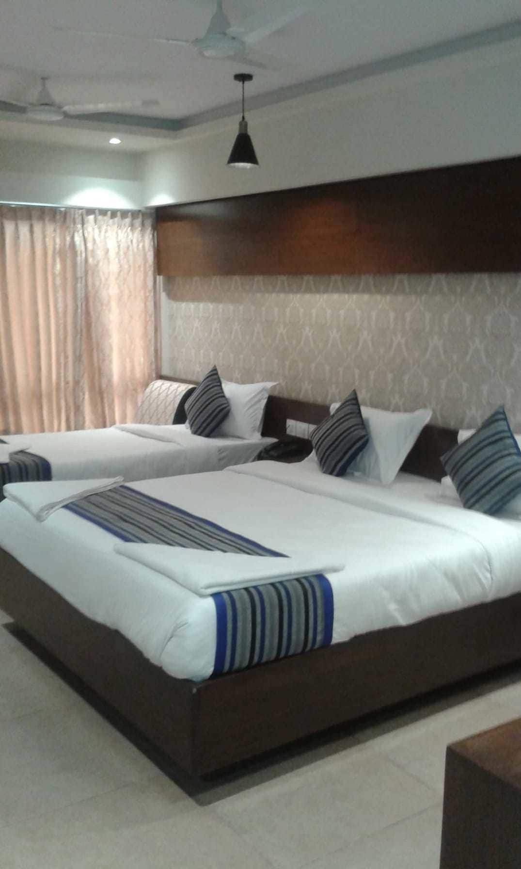 A hotel room with two beds, a ceiling fan, and a patterned wall.