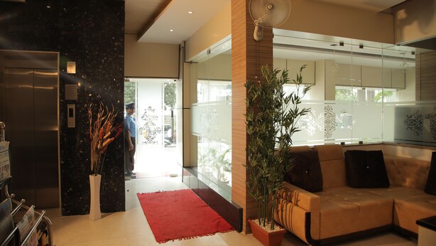 A modern lobby with a reception desk, a red rug, a sofa, and a large fan. - Canyonsun (Chennai)