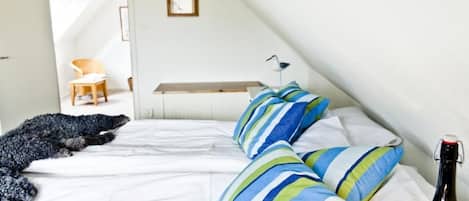 Une chambre à coucher avec un lit, des oreillers, une bouteille et une chaise.