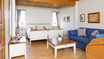 A cozy room with a bed, a blue sofa, a wooden coffee table, and a white dresser.