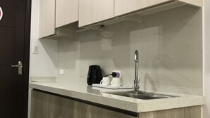 A modern kitchen with a marble countertop, a built-in sink, and wooden cabinetry. - Umali Kayo at Megatower Residences II (Baguio)