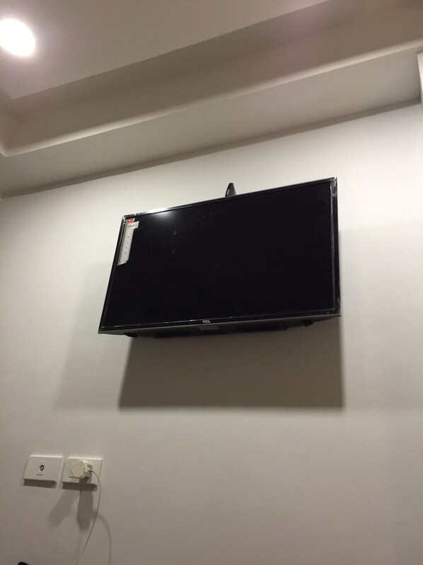 Televisão de tela plana presa em uma parede lisa, com uma tomada de energia abaixo.