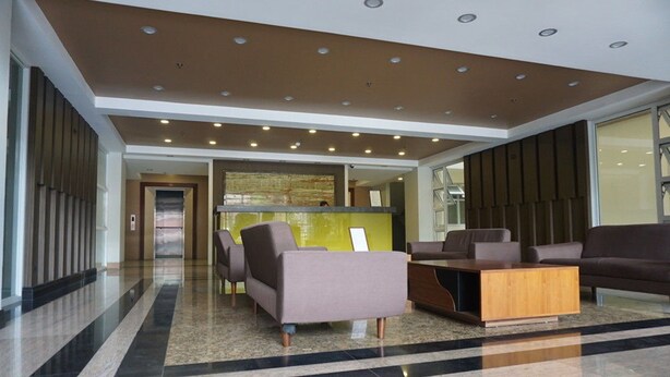 A modern lobby with a reception desk, seating area, and a glass wall. - Umali Kayo at Megatower Residences II (Baguio)