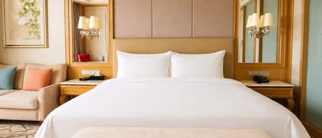 Una camera d'albergo con un letto grande, un comodino con una lampada, una sedia, un tavolino con un telefono e uno specchio fissato alla parete.