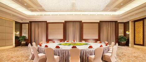 A round table with chairs, a chandelier, and curtains.