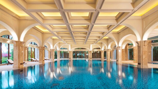 Una gran piscina cubierta con suelo de baldosas y techos abovedados.