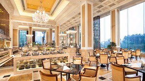 Un vestíbulo de hotel espacioso con una zona de bar central, diferentes disposiciones de asientos y grandes ventanales que ofrecen vistas al exterior.