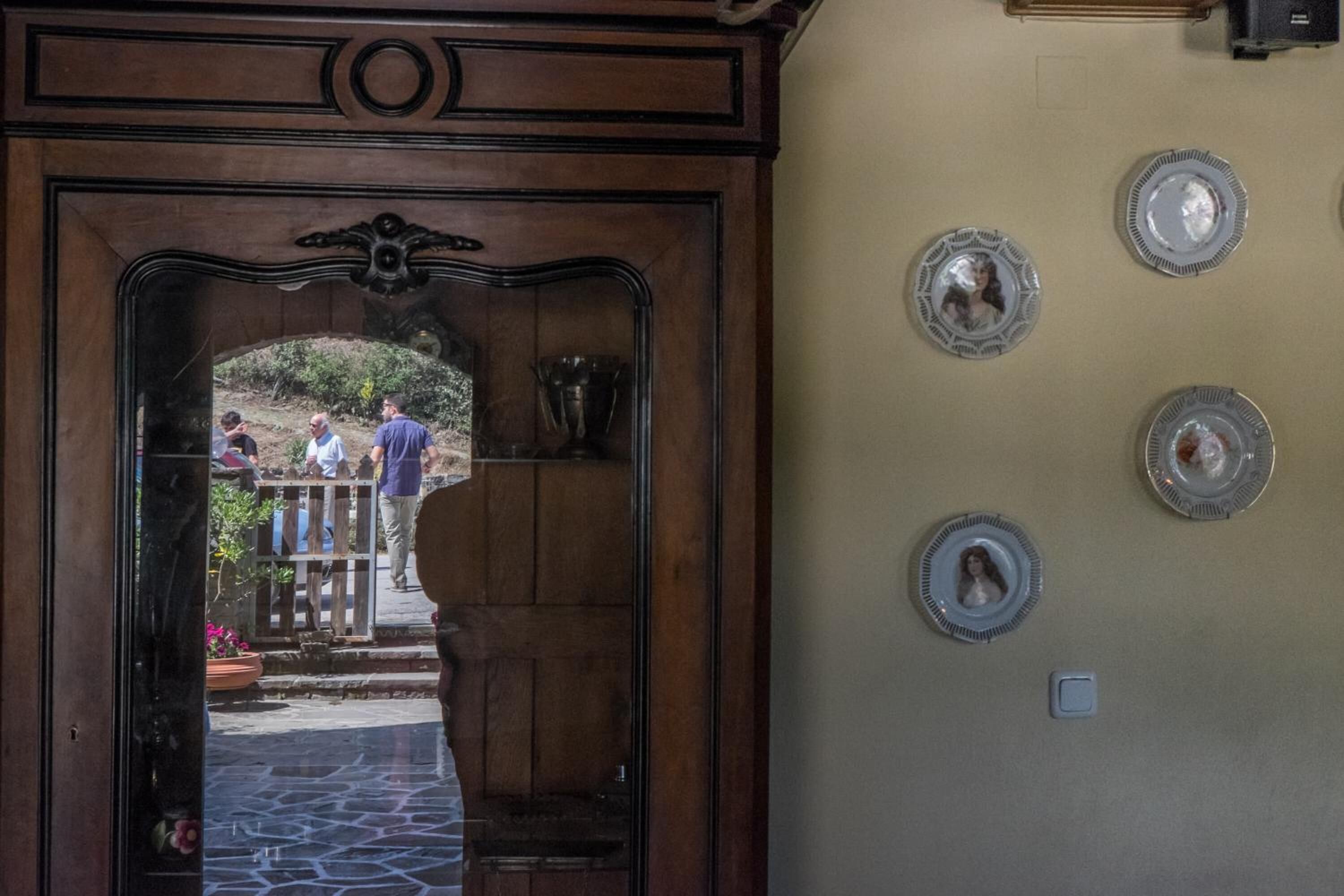 A wooden door with a decorative arch, a stone-paved entrance, and a wall with several framed items.