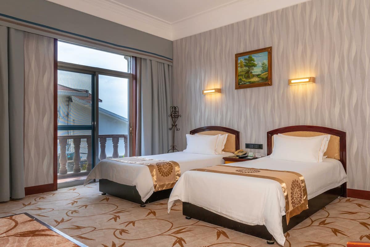 Habitación de hotel con dos camas, un balcón y un cuadro en la pared.