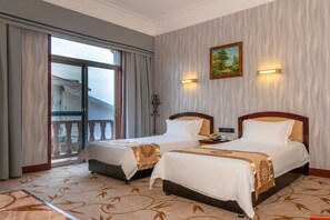 A hotel room with two beds, a balcony, and a painting on the wall.