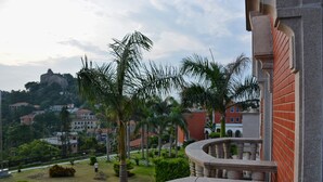 A balcony with a stone balustrade overlooking a landscaped area with palm trees and a distant view of buildings. - Marine Garden Hotel (Xiamen)