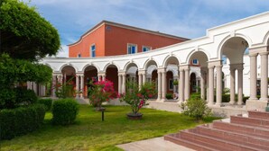 A courtyard with a red building, white columns, and potted plants. - Marine Garden Hotel (Xiamen)