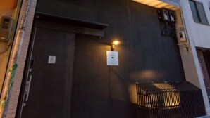 A building with a large black entrance door, a small sign above the door, and a light fixture above the door. - Group STAY CLASSE 02 (Osaka)