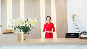 A reception desk with a vase of white flowers, a sign reading "Reception", and a ViewSonic monitor on the right. - Green Hotel Danang (Da Nang)