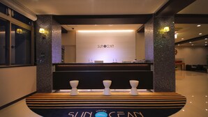 A reception area with a reception desk, three white decorative vases, and a logo on the floor. - Smile Hotel Anan (Anan)