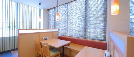 A room with a wooden table and chairs, a bench, and a window with blinds.