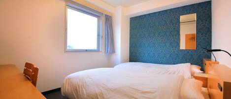 A hotel room with a bed, a desk, a chair, a window with curtains, a nightstand, and a mirror.