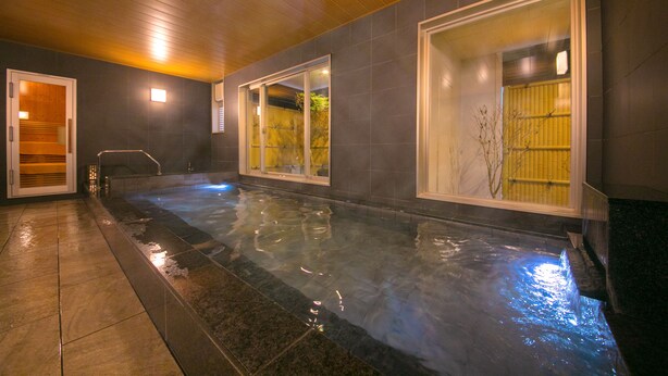 A spa area with a hot tub, wooden ceiling, and tiled walls. - Smile Hotel Anan (Anan)