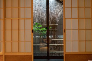 A traditional Japanese room with sliding doors, a tatami mat floor, and a view of a bamboo garden. - Reikaku Kiyomizu-Gojo (Kyoto)
