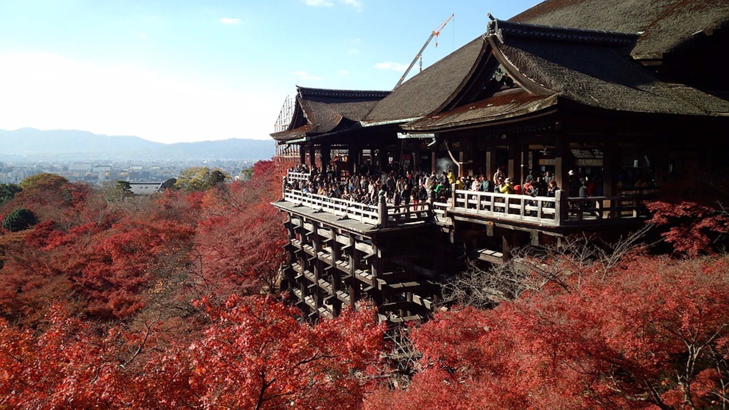 A traditional Japanese building with a wooden structure and a balcony, surrounded by autumn foliage.