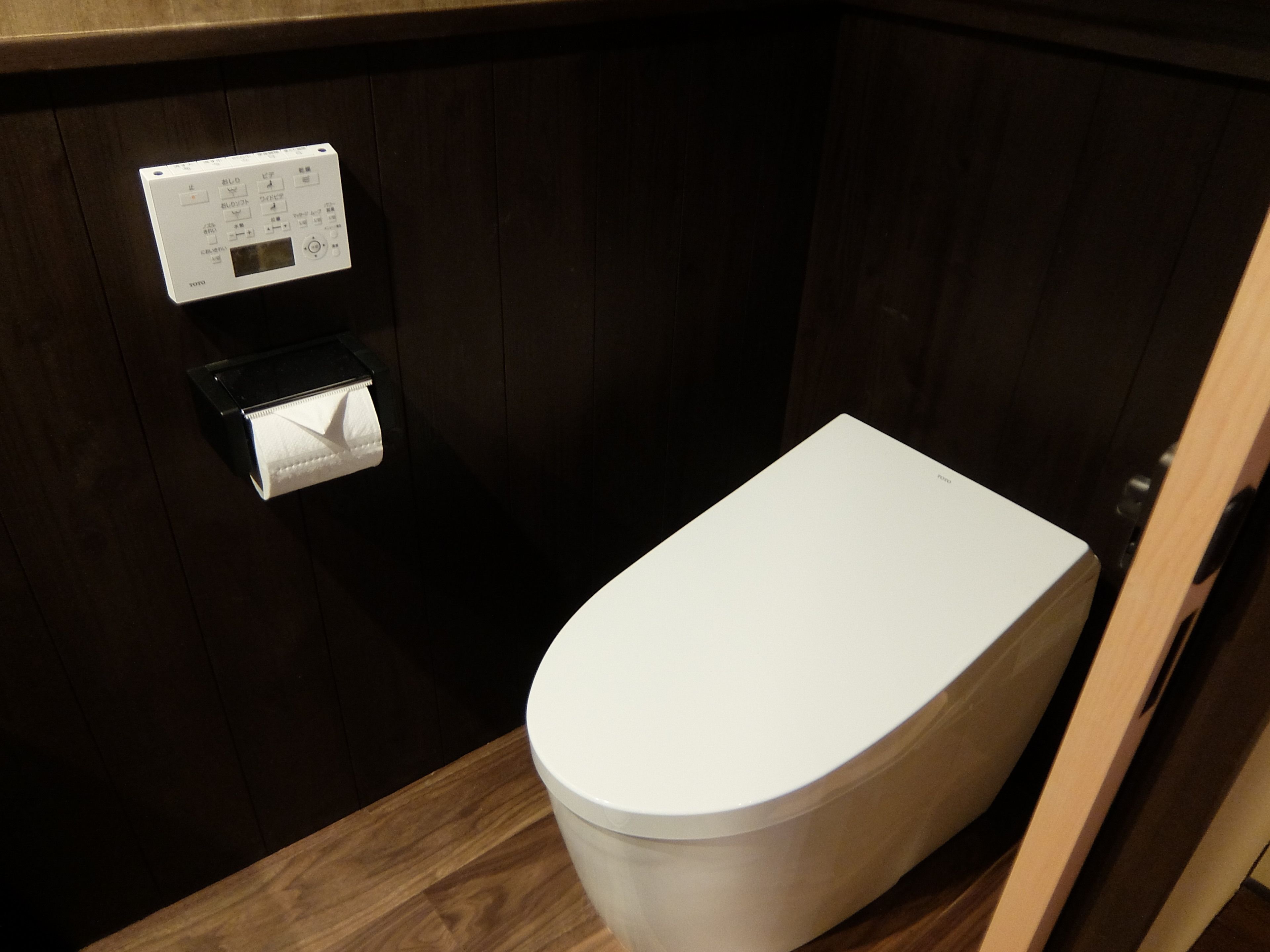Et toilet med kontrolpanel og toiletpapirholder.