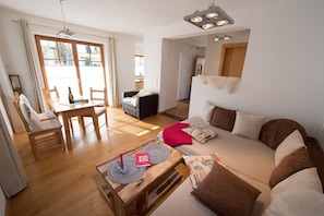 A spacious living area with a sofa, wooden coffee table, and a dining table with chairs. - Ferienwohnung F9 (Garmisch-Partenkirchen)