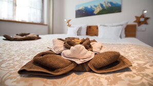 A neatly made bed with a patterned bedspread, a mountain landscape painting on the wall, and a star-shaped decoration. - Ferienwohnung F9 (Garmisch-Partenkirchen)