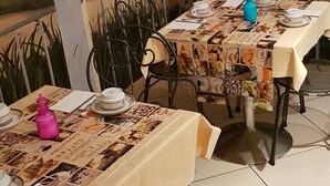 Un comedor con mesas dispuestas para dos, con un mural de paisaje urbano al fondo.