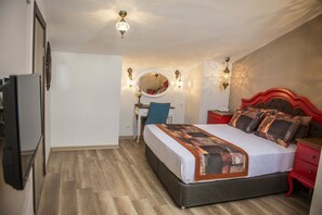 Een slaapkamer met een bed, bureau, stoel, spiegel en kast.