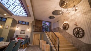 Un comedor amplio con techo alto y ventanas grandes, una escalera de diseño único y una pared decorada con ruedas ornamentales.