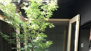 A small, enclosed space with a wooden floor, a small tree, and a tiled wall. - Reikaku Yasaka (Kyoto)