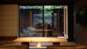 A traditional Japanese room with tatami flooring, a low table, and sliding doors leading to a garden. - Reikaku Yasaka (Kyoto)