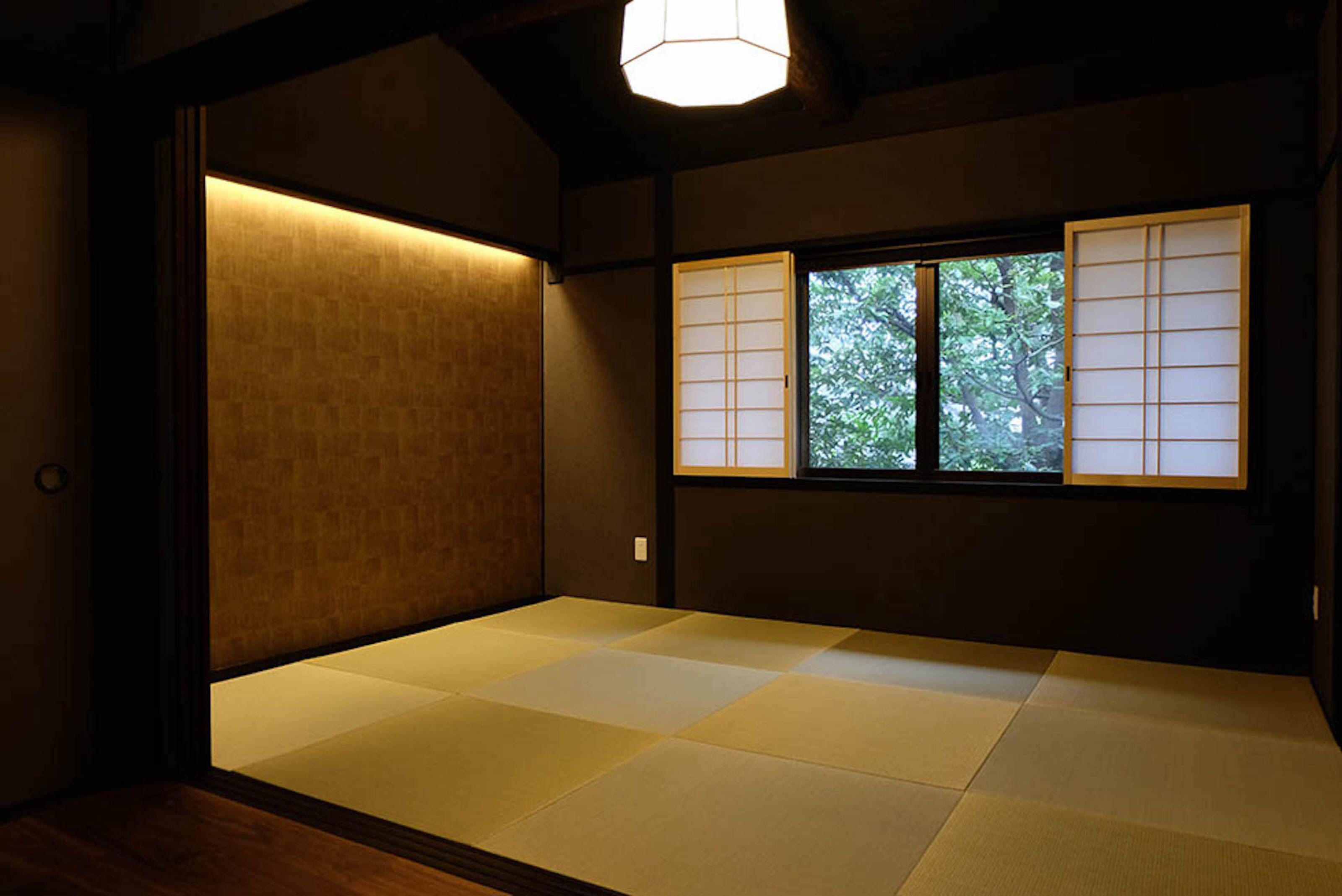 A traditional Japanese room with tatami flooring, sliding doors, and a window with shoji screens.