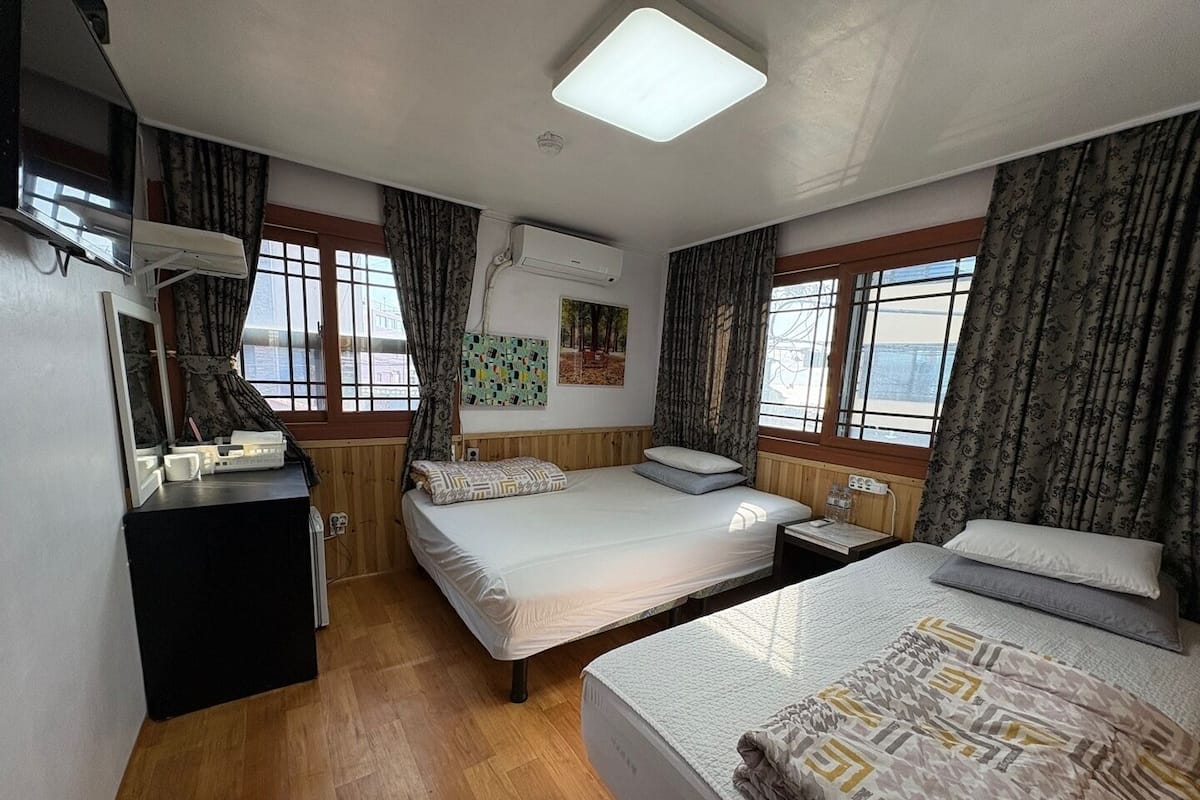 A room with two beds, a desk, and a window.