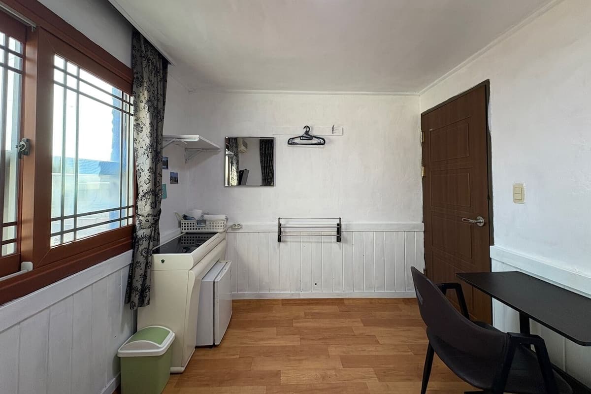 A compact kitchen with a window, a radiator, a small sink, and a table with chairs.