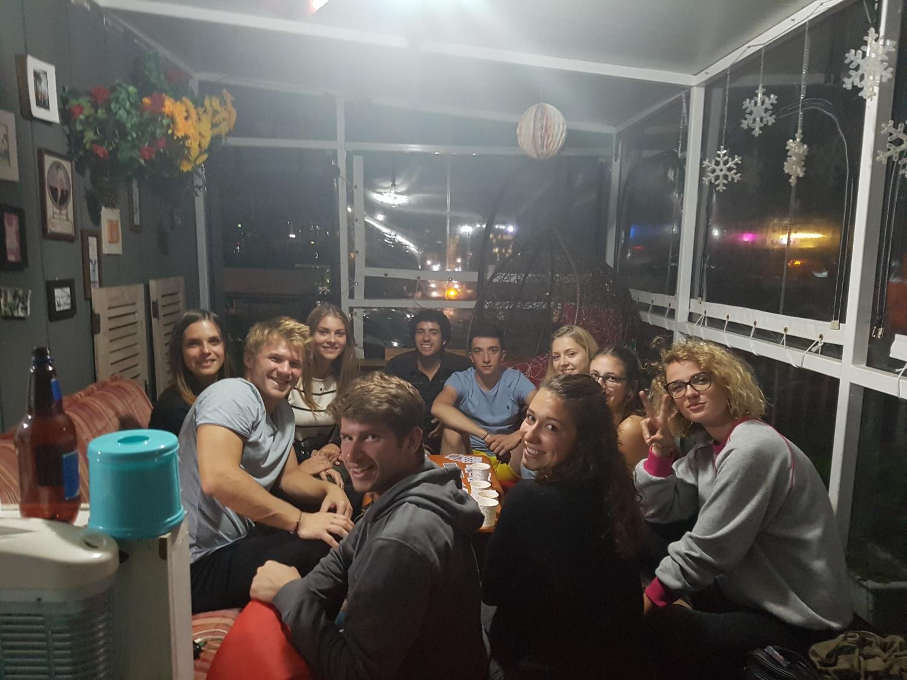 A group of people gathered in a room with a window overlooking a cityscape at night.
