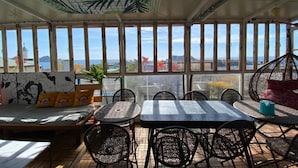 Une terrasse ensoleillée avec une table et des chaises, un banc rembourré et une vue sur la mer.