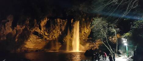 Una cascada nocturna en una cueva con gente alrededor.