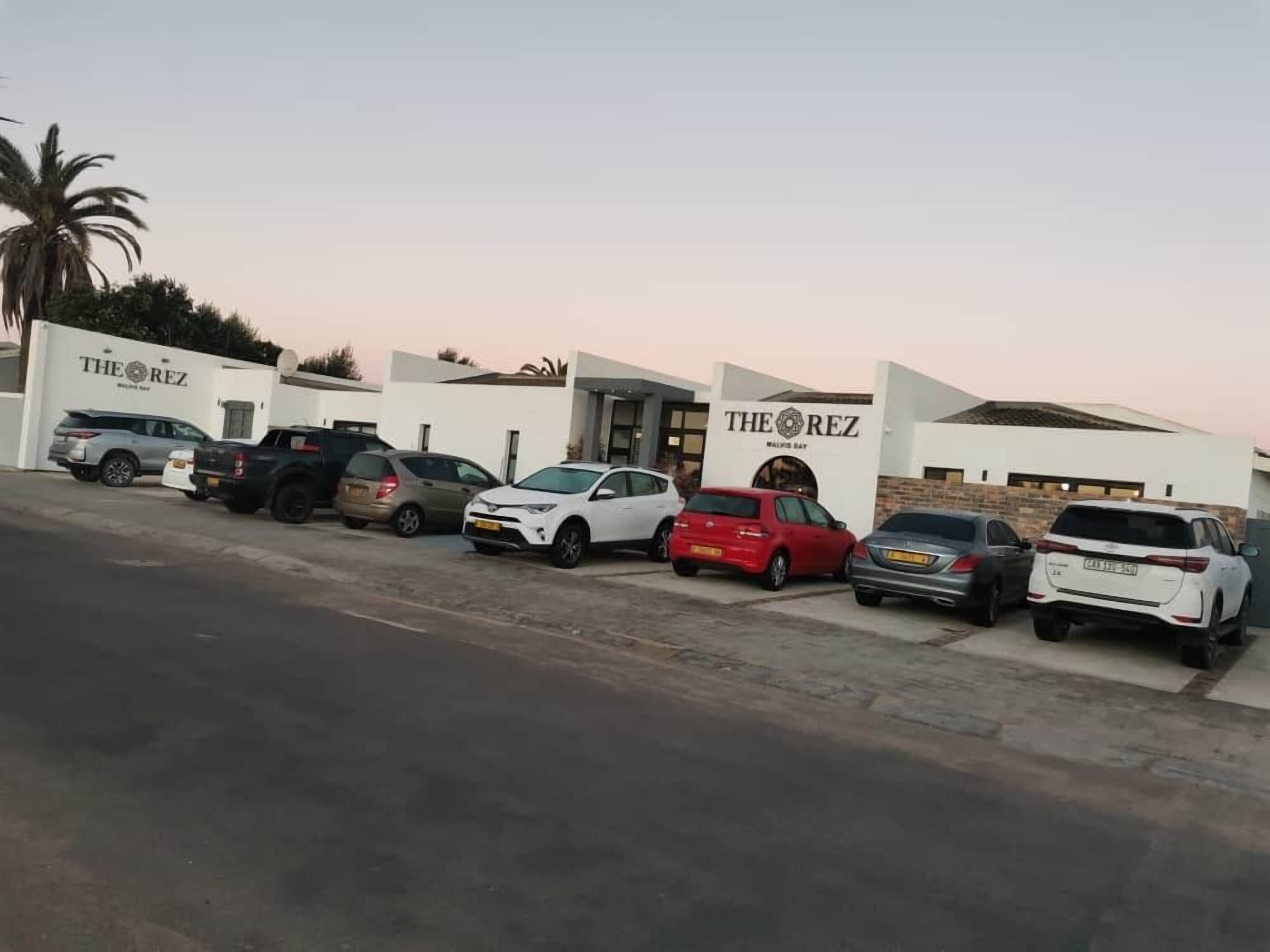 A parking lot with multiple cars parked in front of a building with 'THE REZ' signage.