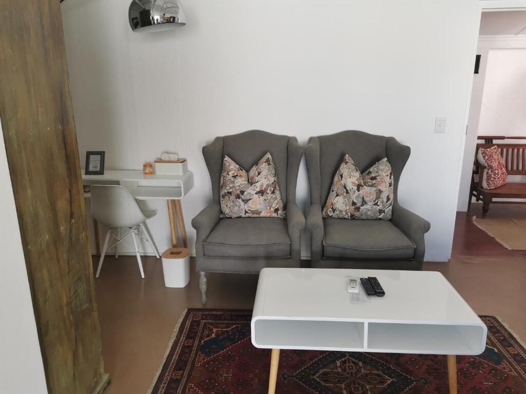 A living room with two grey armchairs, a white coffee table, and a small desk with a chair.